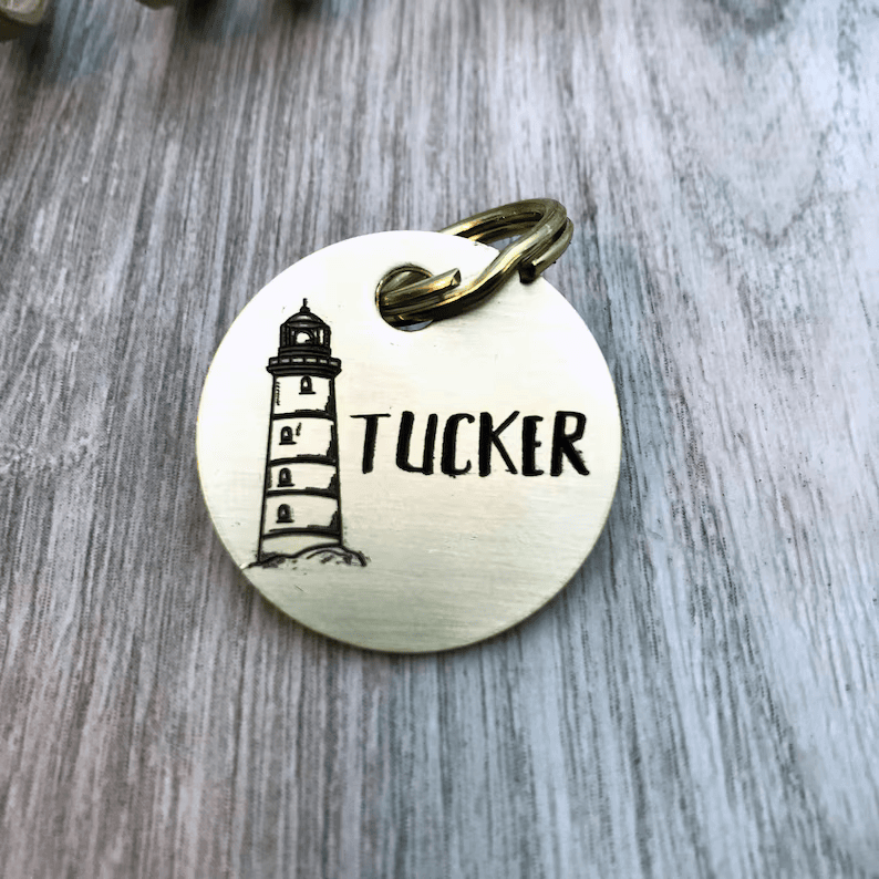 Silver color circular dog tag with engraved lighthouse design
