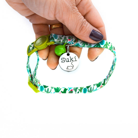 Someone holding cat collar with an ID tag and name Suki on it