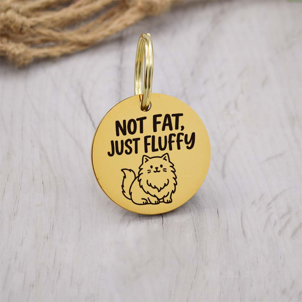 Funny gold pet ID tag with 'Not Fat, Just Fluffy' engraved — personalized dog or cat tag for pet safety and identification.