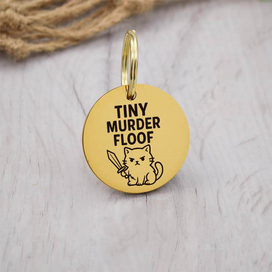 Funny gold pet ID tag with 'Tiny Murder Floof' engraved — personalized dog or cat tag for pet safety and identification.